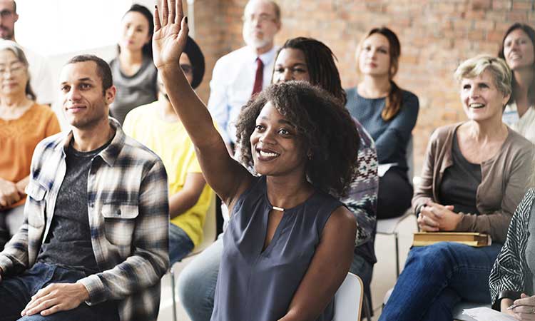 Woman raising her hand in audience at a lecture