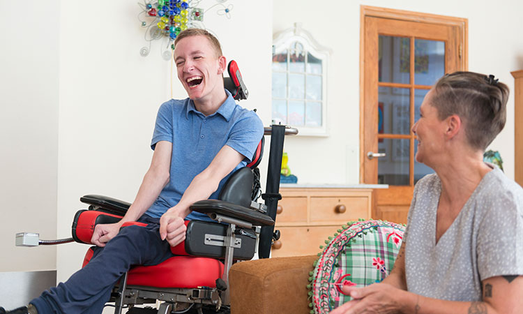 man in wheelchair in community home with female staff member