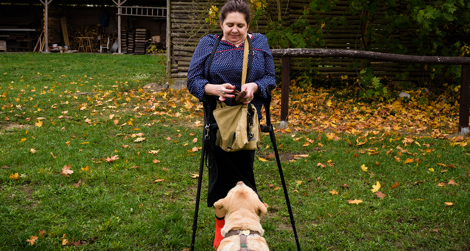 Female rehabilitation patient with canes in park with dog
