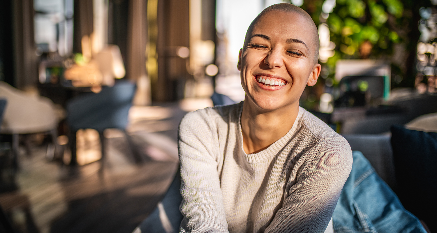 Woman with shaved head smiling in her home