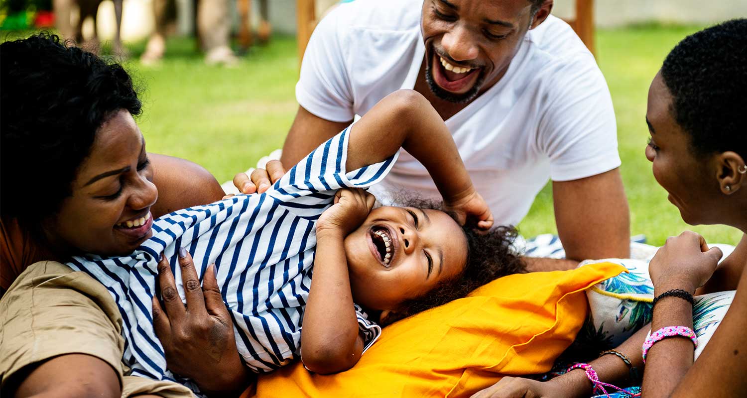 Black family laughing and playing together at the park