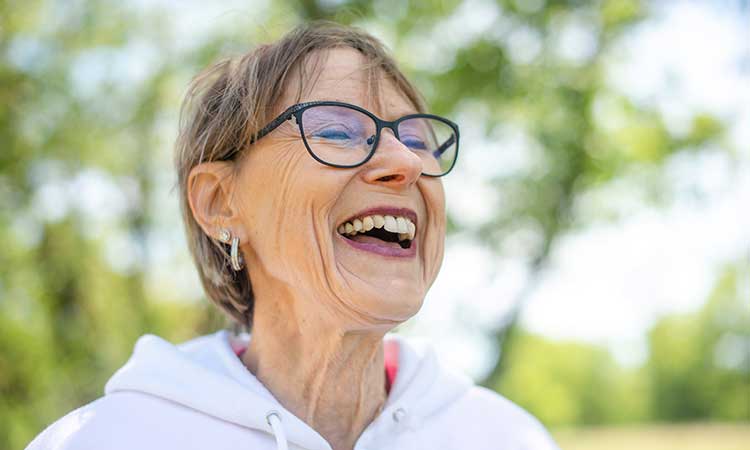 Elder caucasian woman with glasses smiling outside