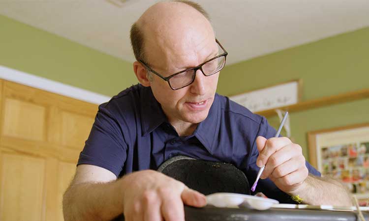 Caucasian man with glasses working on a painting art project in his day program