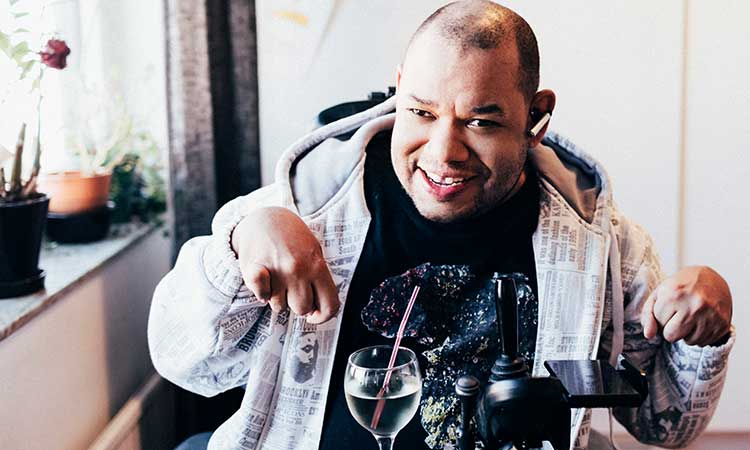 man with disability sitting with headphones in and smiling