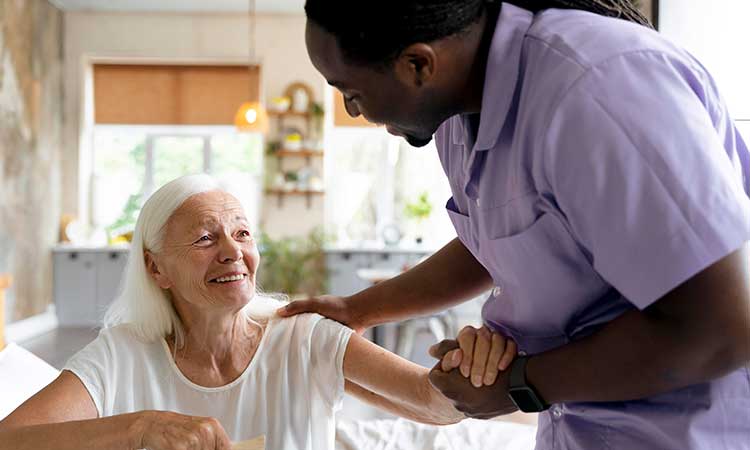 Male nurse supporting elder woman in her home