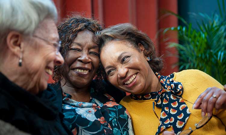 Three senior African-American women sitting close together and smiling