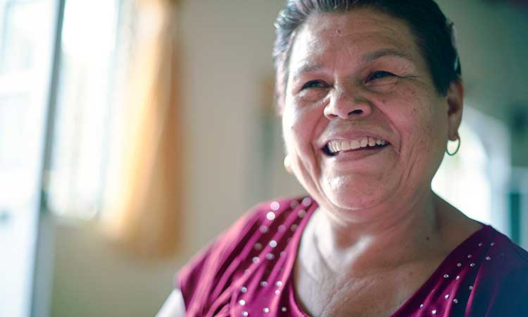 Senior Latina woman with purple shirt smiling at camera