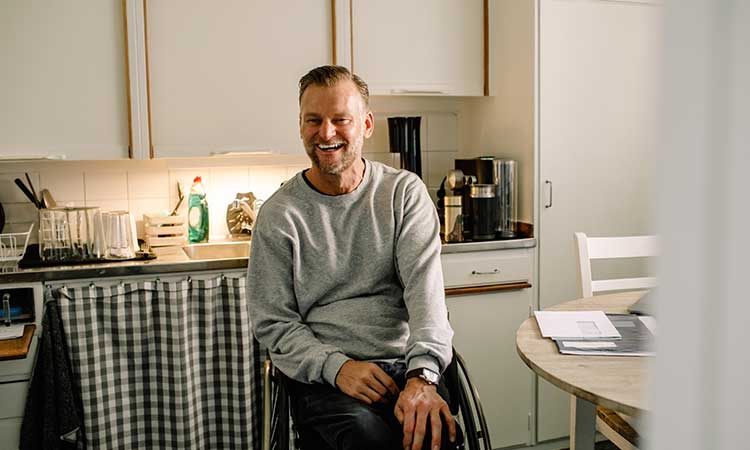man in wheelchair sitting in kitchen and smiling