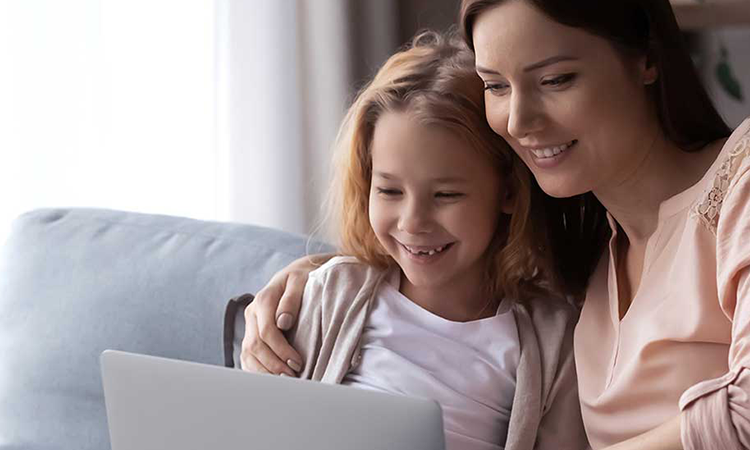 Mother and young daughter looking at a laptop screen and smiling