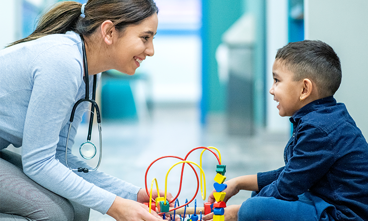 Doctor playing blocks game with young child patient