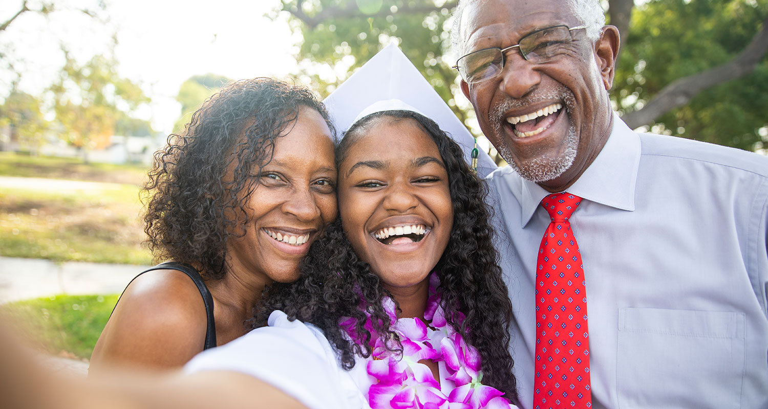Teenage girl taking a selfie with parents at graduation