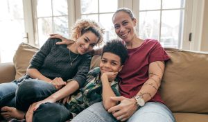 Mom laughing with young son and teenage daughter on the couch