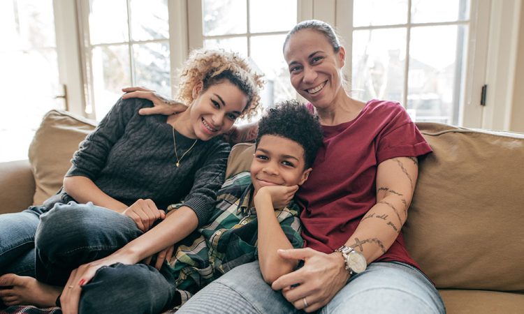 Mom laughing with young son and teenage daughter on the couch