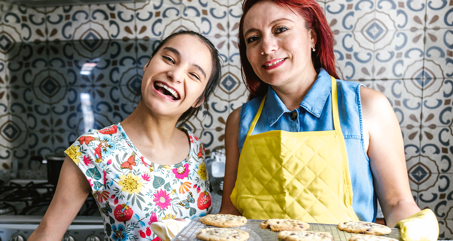 Mom and young adult daughter are baking cookies