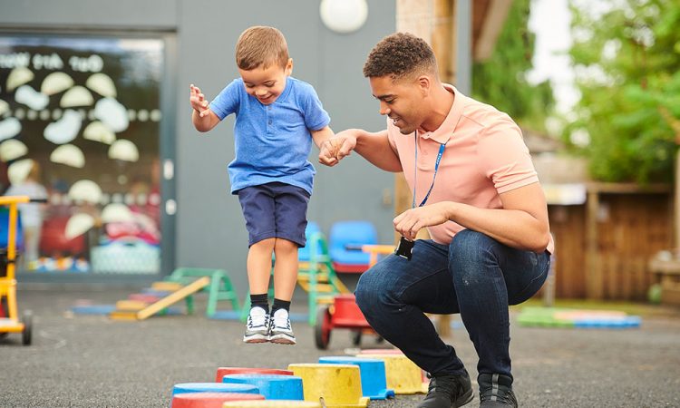 physical therapist helping little boy jump on buckets
