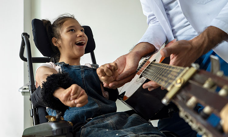 Girl in wheelchair listening to music played on a guitar